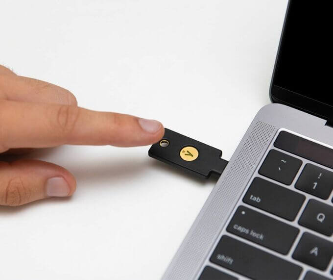 Photo d'un doigt s'apprêtant à toucher la pastille métalique de la Yubikey